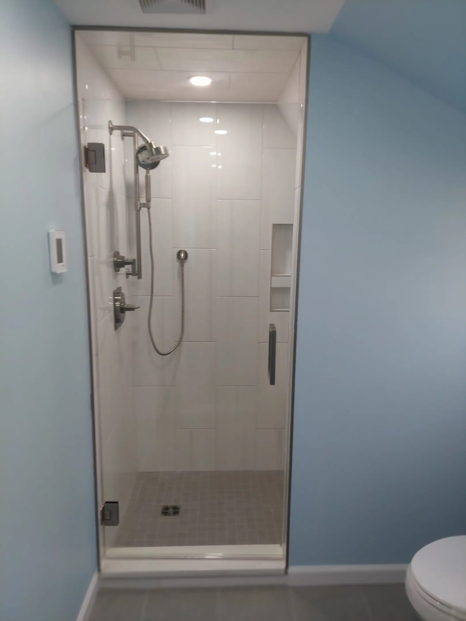Glass door shower with blue walls.