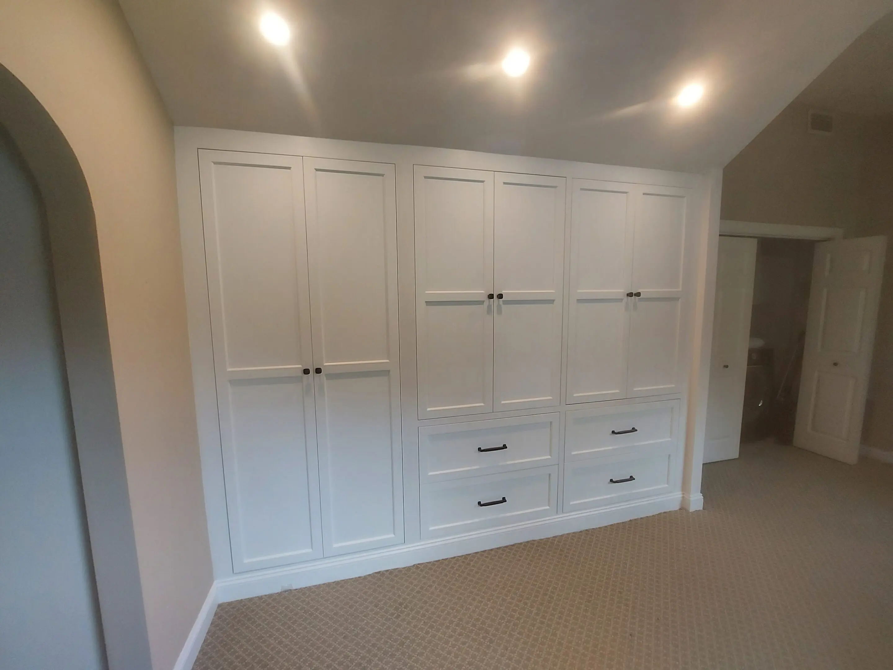 White built-in closet with overhead lighting.