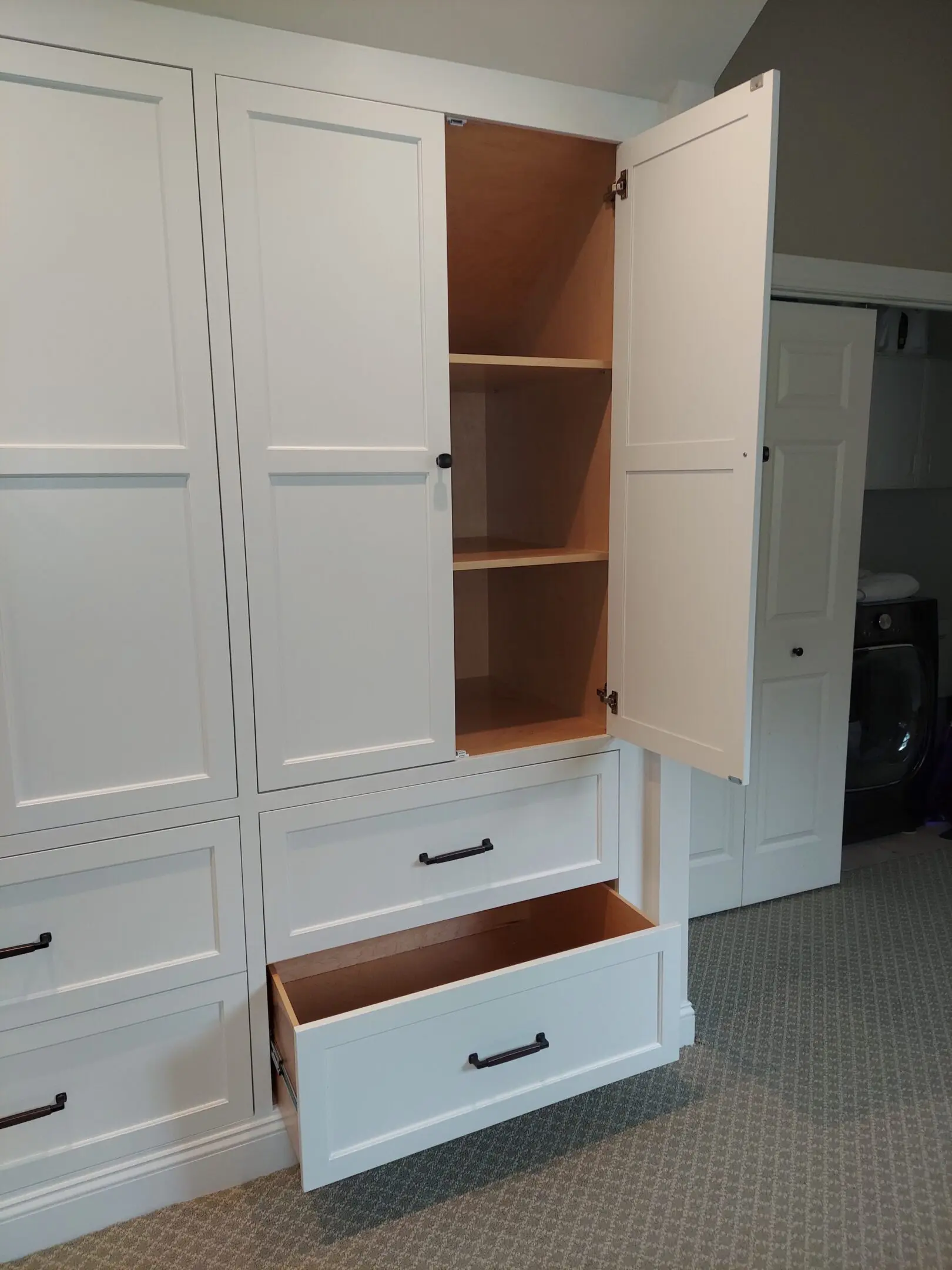 White cabinet with open door and drawer.